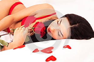 Girl lying in bed, strewn with hearts and roses photo