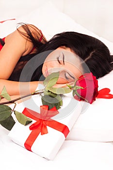 Girl lying in bed, strewn with hearts and roses