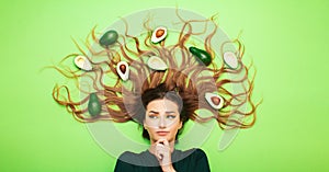 Girl lying on colored background with avocado fruits on long hair, young woman thinking and balance, female head thoughts