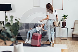 Girl lying on the couch, her mother standing with a suitcase. Travel, lodging