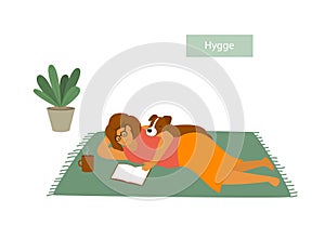 Girl lying down on the floor with her pet dog, reading a book, enjoying being home