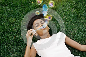 Girl lying on grass blowing bubbles