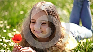 Girl lying on grass, grassplot on background. Girl on dreamy face holds red tulip flower, enjoy aroma. Child enjoy