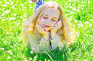 Girl lying on grass at grassplot, green background. Girl on dreamy face spend leisure outdoors. Heyday concept. Child