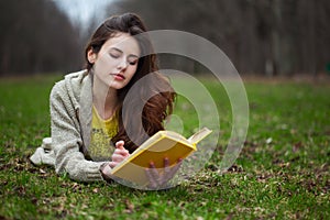 Girl lying in a grass and reading book