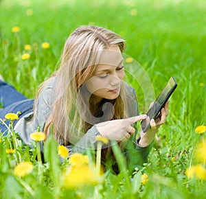 Girl lying on grass with tablet computer