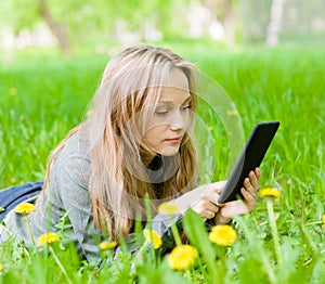 Girl lying on grass with tablet computer