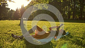 Girl lying in the park on chest and use the Internet on tablet PC.