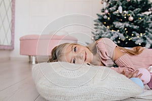 Girl lying on a pillow next to a Christmas tree