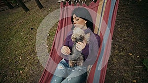 Girl lying with puppies in hammock in autumn park