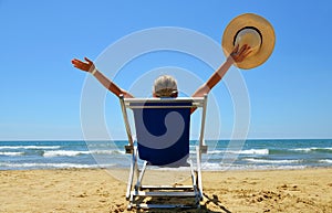 Girl lying on a sun lounger on sandy beach.