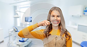 Girl with magnifier shows teeth at dental clinic