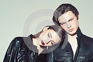Girl with make up lean on male shoulder, grey background. Couple on calm faces dressed in fashionable clothes. Fashion