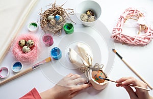 girl is make wickerwork of beads and eggs for happy easter