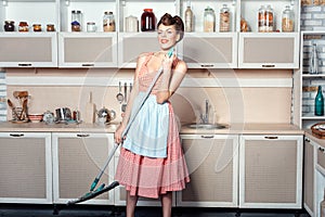 Girl makes cleaning the kitchen and sings.