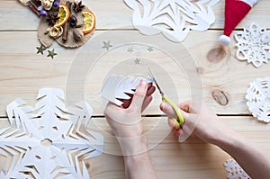 The girl makes a homemade snowflakes cut out of paper, preparation for the new year, Christmas