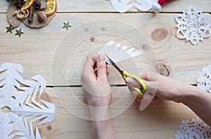 The girl makes a homemade snowflakes cut out of paper, preparation for the new year, Christmas