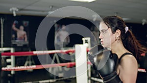 Girl makes punches. Sportive young coach and woman have training in the boxing ring. MMA octagon training.