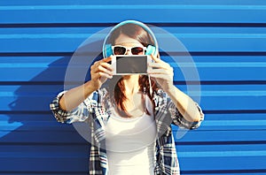 Girl makes self-portrait on smartphone and listens to music in headphones, screen phone