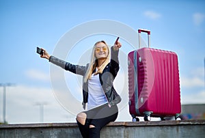 A girl makes selfie on a background of a pink suitcase