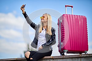 A girl makes selfie on a background of a pink suitcase
