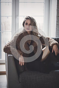 Girl with makeup in coat sitting at floor at home