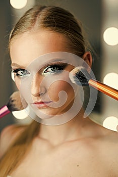 Girl makeup face with powder brushes in beauty salon. Girl skin, skincare, cosmetics.
