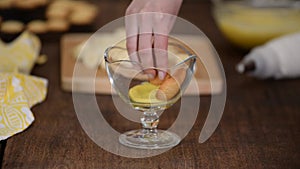 The girl making banana pudding in glass glasse in the kitchen. Banana dessert in a glass.
