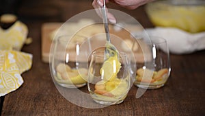 The girl making banana pudding in glass glasses in the kitchen. Banana dessert in a glass.