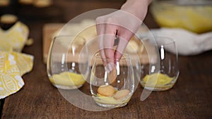 The girl making banana pudding in glass glasses in the kitchen. Banana dessert in a glass.