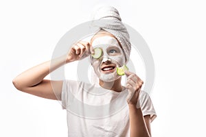 Girl making clay facial mask and and cucumber on eyes. Teenage girl doing anti blemish skin treatment. concept of natural