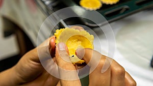 A girl making egg tart in a mold on a black tray