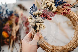 Girl making floral door wreath from colorful dry summer flowers