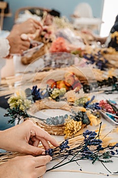 Girl making floral door wreath from colorful dry summer flowers and plants.