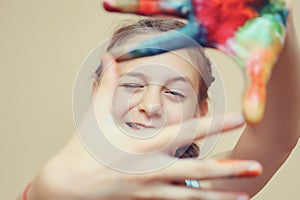 Girl making frame with hands in paints