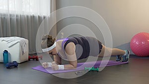 Girl making great effort to stand in plank position, working hard to lose weight