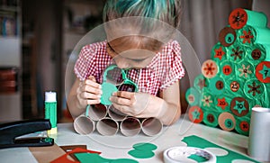 Girl making handmade advent calendar with toilet paper rolls at home. Seasonal activity for kids