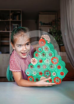 Girl making handmade advent calendar with toilet paper rolls at home. Seasonal activity for kids