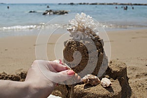 Girl is making a Sandcastle with coral on sandy beach