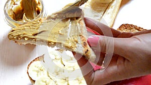 Girl making a sandwich. spooning peanut butter out of a can. Toasted bread with tasty peanut butter on  table