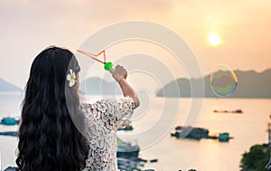 Girl making soap bubbles on seaside at sunset