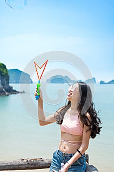 Girl making soap bubbles with seaside view