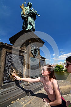 Girl making a wish. Statue of St. John of Nepomuk. Charles Bridge. Prague. Czech Republic