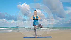 The girl is making yoga pose on beach in Vietnam. Sea or ocean happy woman relaxation. Water and waves. Hands and blue