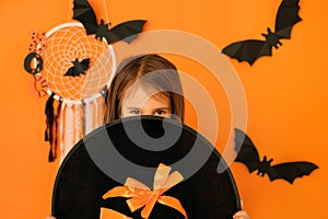 A girl with a malicious look looks out from behind a big witch hat