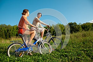 Girl and man go for drive on bicycles in sunny day