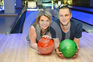 Girl and man lie on parquet in bowling club