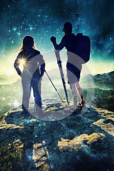 Girl and man standing with a tripods and cameras on high peak