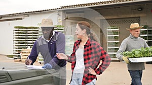 Girl manager discussing with men workers delivery of seedlings to the farm at a warehouse