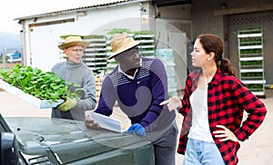 Girl manager discussing with workers delivery of seedlings to farm